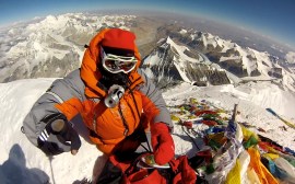 Edita pointing a finger to the south on the Summit of Mt Everest
